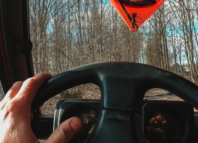 Driver's point-of-view from the cab of a diesel truck hauling gear on a country road